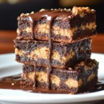 A plate of perfectly cut fudgy cake crumb brownies stacked on top of each other, with melted chocolate dripping from the top. The image conveys richness, indulgence, and the ultimate dessert satisfaction